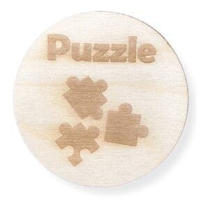 Okrągła drewniana plakietka o średnicy 7,8 cm z wygrawerowanym napisem Puzzle i trzema elementami puzzli.