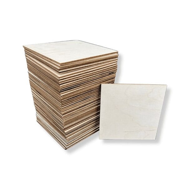 Drewniane Kwadraty ze Sklejki 11 x 11 cm 50 szt Duża pula drewnianych kwadratów ze sklejki 11 x 11 cm w ilości 50 sztuk ułożona w wysoką stosową wieżę z pojedynczą płytką obok.