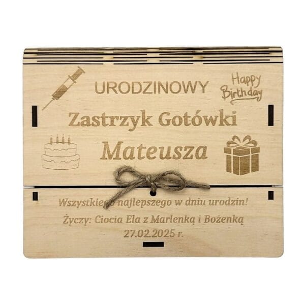 Drewniane pudełko koperta z grawerem na urodziny Mateusza, przewiązane sznurkiem jutowym, ozdobione wygrawerowaną strzykawką, tortem i życzeniami.