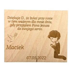 Drewniany magnes personalizowany na komunię ze sklejki o wymiarach 9 x 7,5 cm z grawerem tekstowym, gołębicą i modlącym się chłopcem o imieniu Maciek.