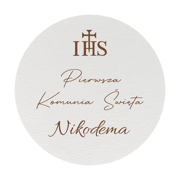 Zbliżenie na minimalistyczną, białą płytę HDF z nadrukiem IHS i napisem Pierwsza Komunia Święta Nikodema.