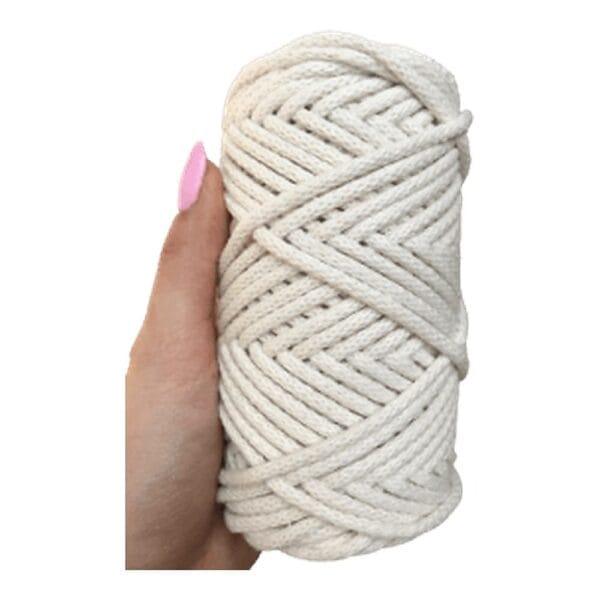 Sznurek Bawełniany z Rdzeniem 5 mm Kość Słoniowa 50 m Sznurek bawełniany z rdzeniem 5 mm kość słoniowa 50 m zwinięty w motek i trzymany w dłoni.